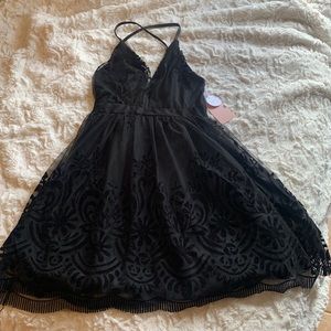 Black short dress with black velvet designs .